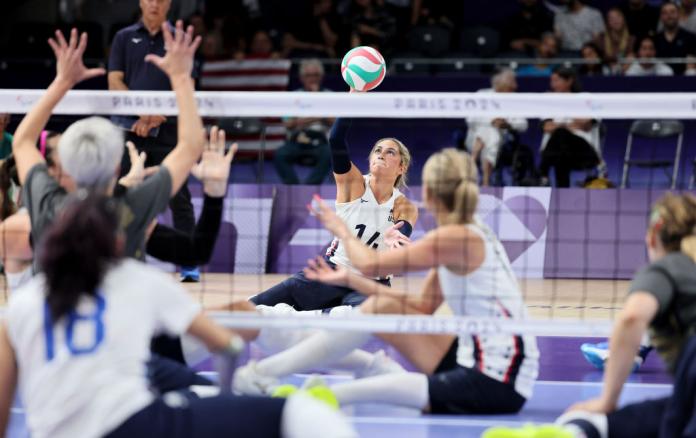 A female sitting volleyball player spikes a ball during a game. 