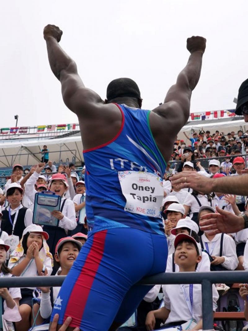 A man waving to a group of children in a stadium stand